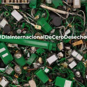 Montón de residuos electrónicos en tonos verdes (cables, piezas, dispositivos y componentes mezclados) con el texto “#DíaInternacionalDeCeroDesechos” en el centro y el logo de ReciRAEE en la esquina inferior derecha